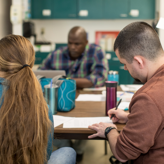 A group of nursing students sit at a table with textbooks.